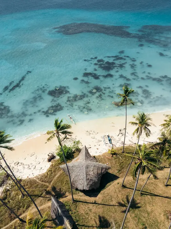 Aerial view of a bangka boat over a palm-fringed reef