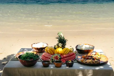 Private island lunch setup on white sand in El Nido, Palawan — grilled seafood and tropical fruit