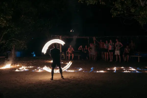 Bailarín de fuego en la playa por la noche