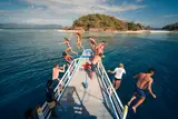 Group of travelers jumping off the Seatours expedition boat bow into turquoise water during a private 3D2N Palawan expedition charter